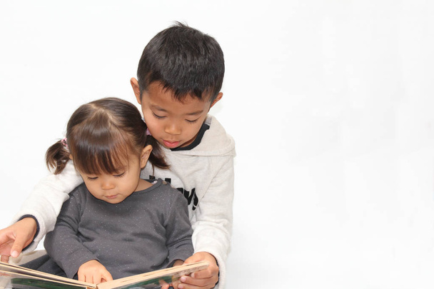 Japán testvérpár olvasó egy képeskönyv (7 éves fiú és 2 év régi lány) - Fotó, kép