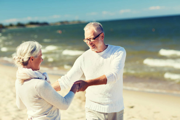 happy senior couple holding hands on summer beach - Zdjęcie, obraz