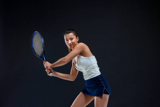 Portrait of beautiful girl tennis player with a racket on dark background - Photo, Image