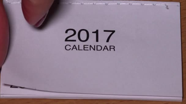 weibliche Hand öffnet Januarseite auf kleinem Jahreskalender 2017. - Filmmaterial, Video