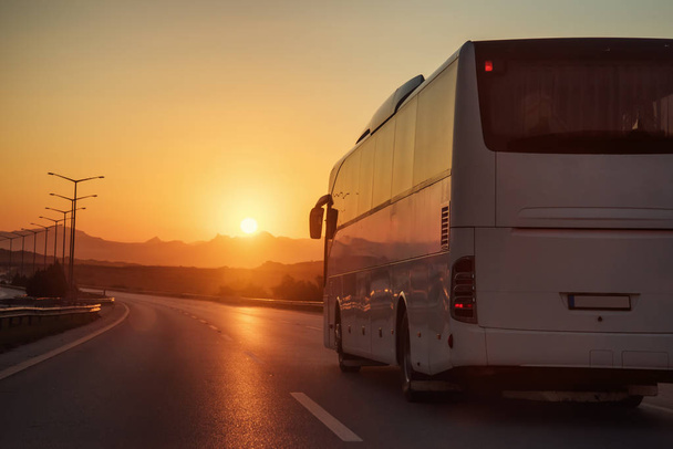 White bus driving on road towards the setting sun - Foto, Imagem