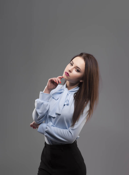 Girl in blue shirt, gray background. Joyful young fashion smiling brunette woman with pink lipstick and crossed hands. Portrait - Valokuva, kuva