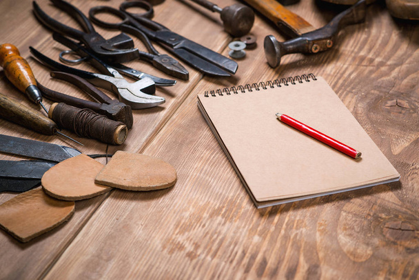 Juego de herramientas, cuaderno, lápiz para zapatero sobre fondo de madera
. - Foto, Imagen