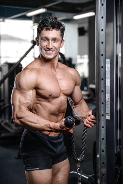 Handsome bodybuilder training in the gym sexy man lift dumbbells - Valokuva, kuva