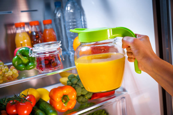 Woman takes the Orange juice from the open refrigerator - Fotografie, Obrázek