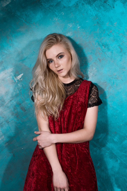 Beautiful blonde girl in a red dress posing against a wall green - Foto, Imagen