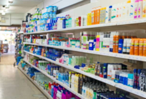 Imagen borrosa de estantes con champús y productos químicos para el hogar en el supermercado
. - Foto, Imagen