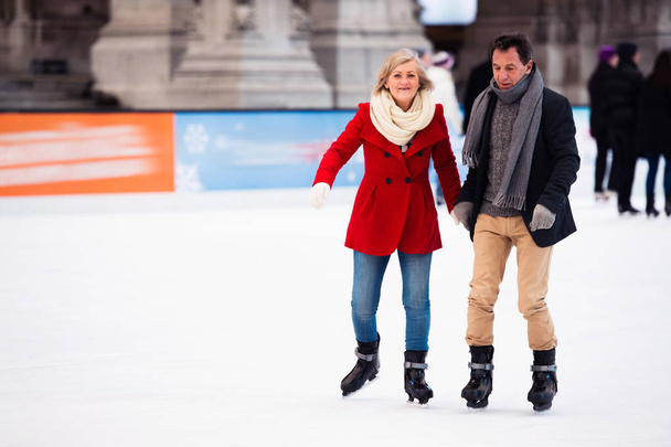 Beautiful senior couple ice skating in city centre. Winter - Foto, afbeelding