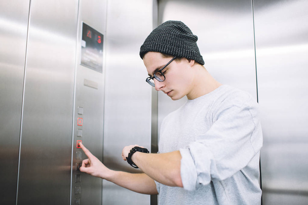 Young stylish guy standing in elevator - Фото, изображение