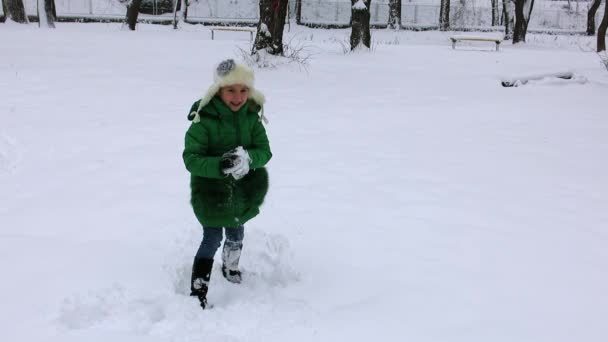 Vrolijk meisje, sneeuwbal gooien bij iemand krijgt terug een sneeuwbal. Sneeuwballengevecht in de winter.  - Video