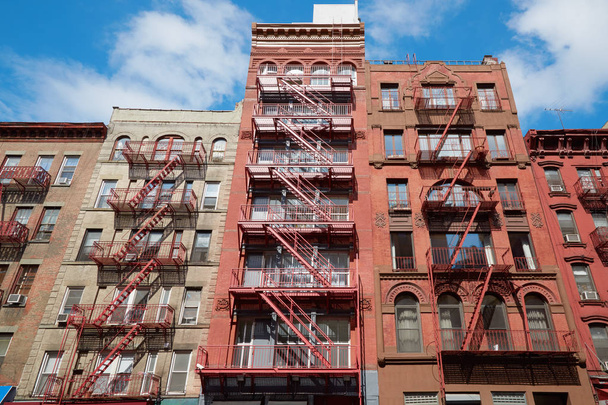 Typical building facades with fire escape stairs, sunny day in New York - Fotoğraf, Görsel