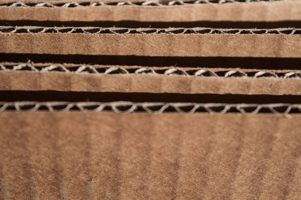 Texture of layered brown cardboard side. Folded cardboard boxes. - Foto, afbeelding