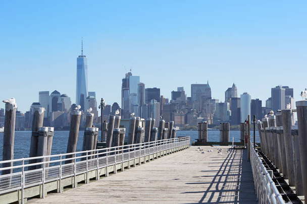 New York city skyscrapers and empty pier with seagulls, sunlight - Foto, Imagem