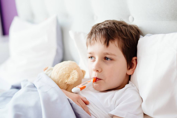 Sick little child with temperature in bed. - Фото, изображение