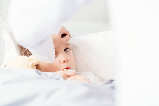 Больной ребенок с температурой в постели
. - Фото, изображение