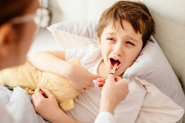 Médico examina enfermo chico garganta
 - Foto, Imagen