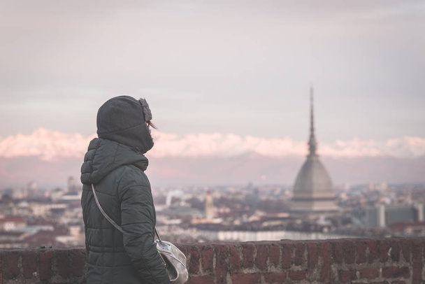 Tourist looking at panoramic view of Torino (Turin, Italy) from balcony above. Winter time, snowcapped Alps in the background. Selective focus, vintage style, toned image. - Photo, Image