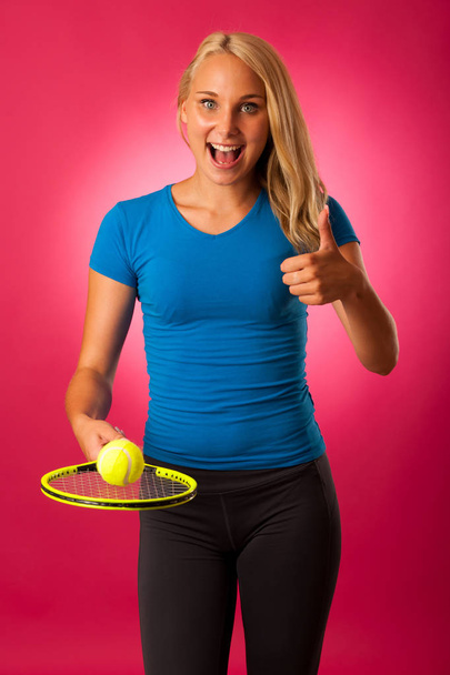 fit young woman with tennis racket and ball over pink background - Foto, imagen