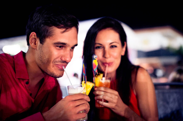 Pareja joven disfrutando de cócteles en una noche de fiesta
 - Foto, Imagen