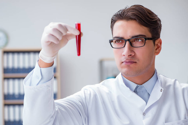 Fiatal orvos a laborban, piros cső - Fotó, kép