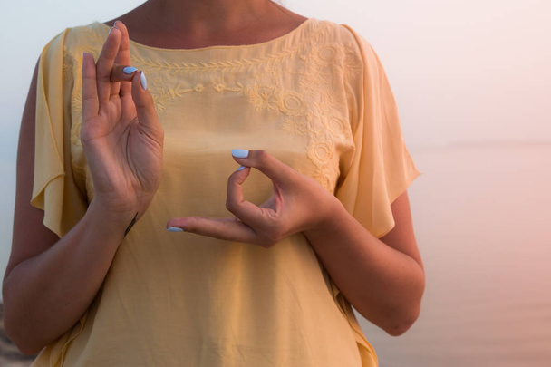 χέρι μιας γυναίκας διαλογισμό σε στάση γιόγκα στην παραλία στο ηλιοβασίλεμα - Φωτογραφία, εικόνα