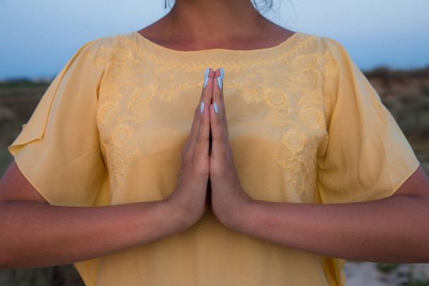 hand van een vrouw mediteren in een pose van de yoga op het strand bij zonsondergang - Foto, afbeelding