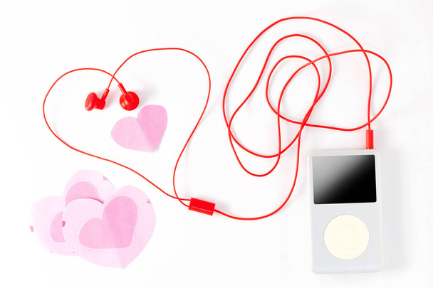 muziekspeler met rode oortelefoon en papier opmerking op wit  - Foto, afbeelding