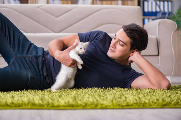 Joven hombre guapo jugando con gatito blanco
 - Foto, imagen