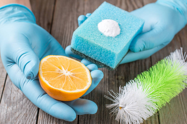 Экологичные натуральные чистящие средства для выпечки соды, лимона и ткани на деревянном столе в руке
 - Фото, изображение