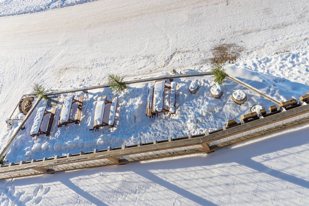 Holztische im Freien mit Schnee auf der Terrasse der Berghütte - Foto, Bild