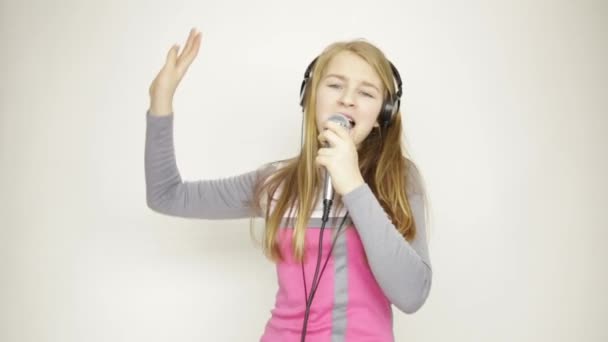 young girl listening music on headphones holding microphone, singing and funy dancing - Кадри, відео
