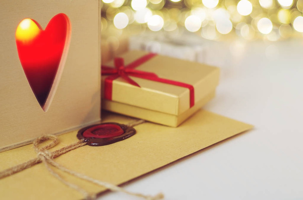 Envelope with wax seal surrounded by gift and a candle in the wooden box with heart shaped hole  - Фото, зображення