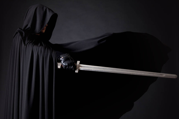 Portrait of a courageous warrior wanderer in a black cloak and sword in hand. - 写真・画像