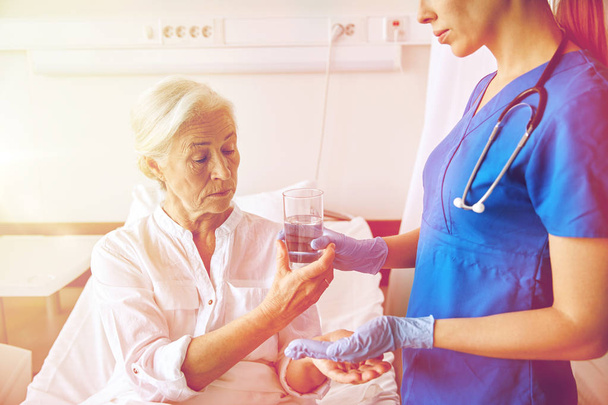 Krankenschwester gibt Seniorin im Krankenhaus Medikamente - Foto, Bild
