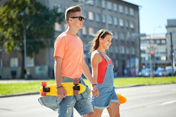 teenage couple with skateboards on city street - Zdjęcie, obraz