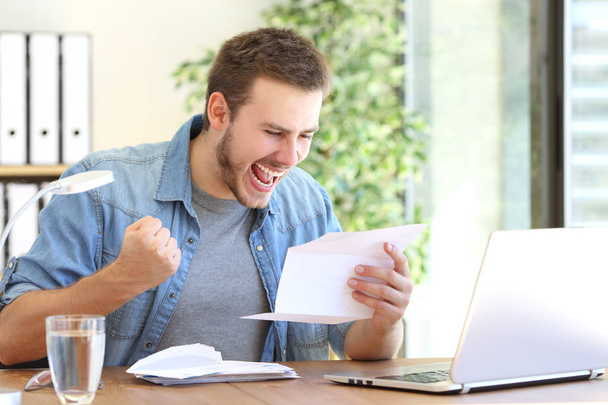 Excited entrepreneur reading a letter - Фото, изображение