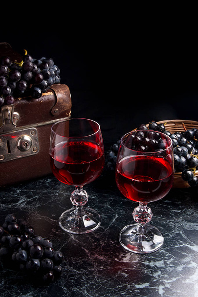 Glass of red wine on dark marble background. Cluster of blue gra - Photo, Image