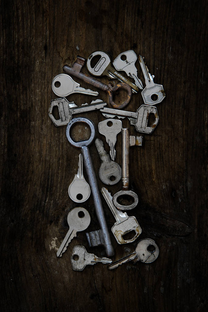 Various old keys in the form of a keyhole on a dark rustic woode - Foto, Imagem