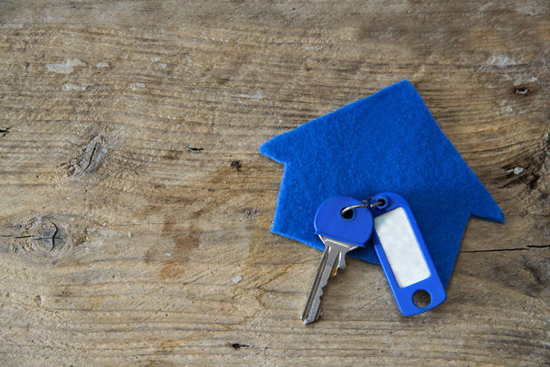Huis van blauwe stof en een sleutel met een lege zeer belangrijke ketting op rustieke wo - Foto, afbeelding