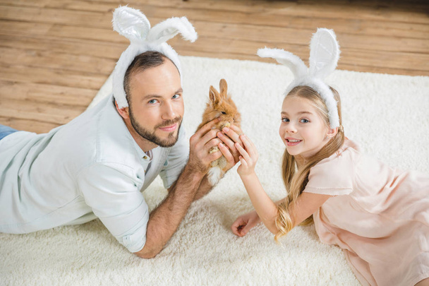 Father and daughter playing with rabbit  - Фото, зображення