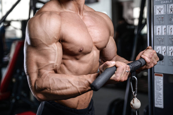 Handsome bodybuilder training in the gym sexy man lift dumbbells - Fotografie, Obrázek