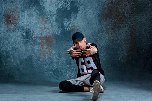 Young man break dancing on wall background. - Photo, image