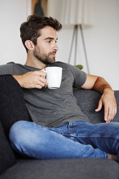 Man enjoying coffee on couch - Фото, изображение