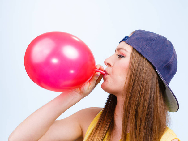 Teen dziewczyna dmuchanie czerwony balonik. - Zdjęcie, obraz
