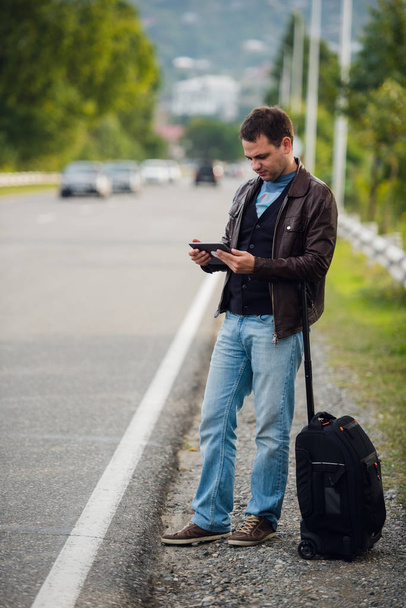 man standing with digital tablet waiting for car or taxi. Hitchhiking - Foto, imagen