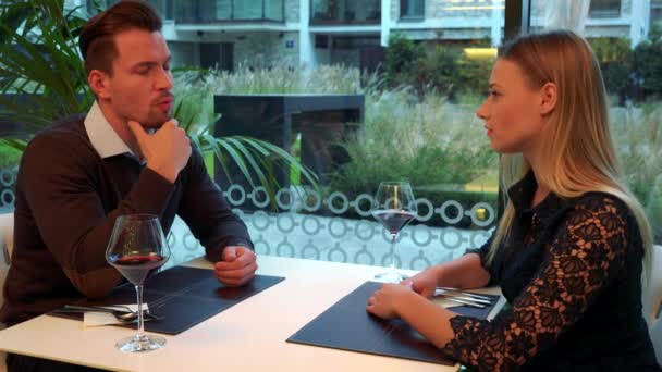 Een man en een vrouw (zowel jonge en aantrekkelijke) stellen aan een tafel in een restaurant - Video