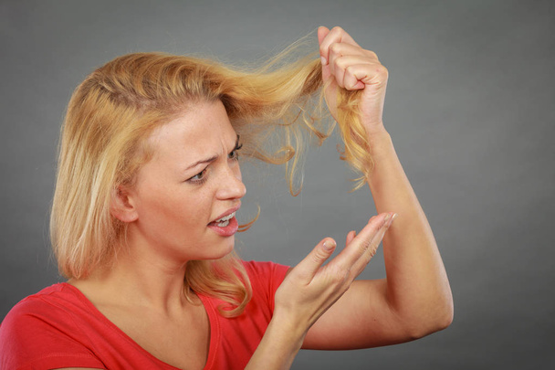 Sad woman looking at damaged hair ends - Фото, зображення