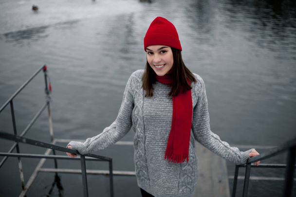 Kız kırmızı şapka ve göl kenarında kış Park'ta yürüyordunuz eşarp. - Fotoğraf, Görsel