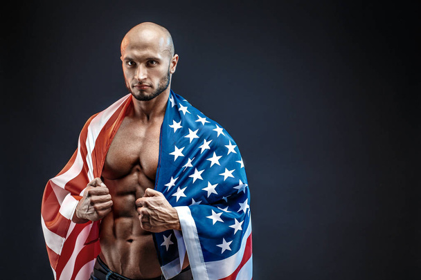 Portrait of bald strong bodybuilder in American flag in studio. Isolated. - Foto, imagen