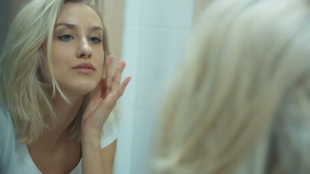 Young woman checking her face in bathroom mirror at home. - Filmmaterial, Video